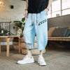 Man wearing light blue patchwork cropped pants with white sneakers
