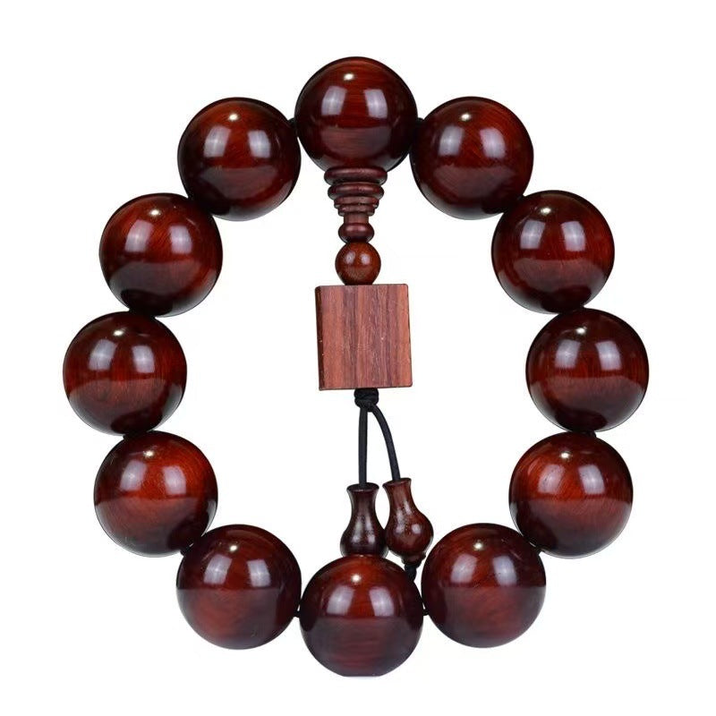 Close up of a red sandalwood beaded bracelet with a square wooden charm