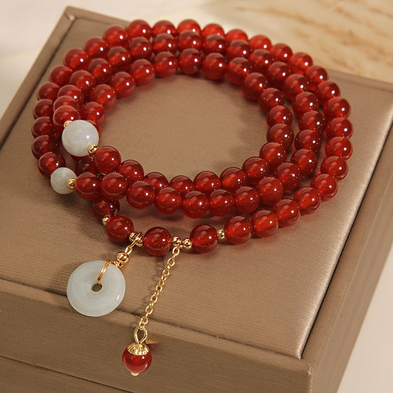 Triple wrap red agate bracelet with jade peace buckle on a box