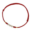 Close-up of a thin red braided cord bracelet with small silver beads against a white background