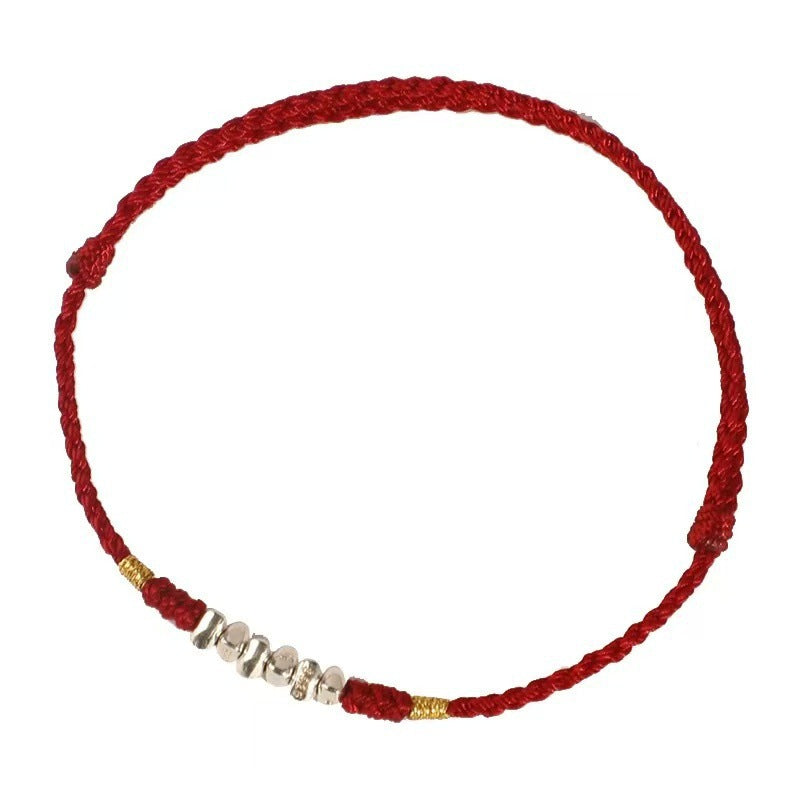 Close-up of a thin red braided cord bracelet with small silver beads against a white background