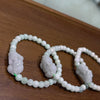 A close-up of three pale green jade bracelets with carved Pixiu charms resting on a wooden surface.