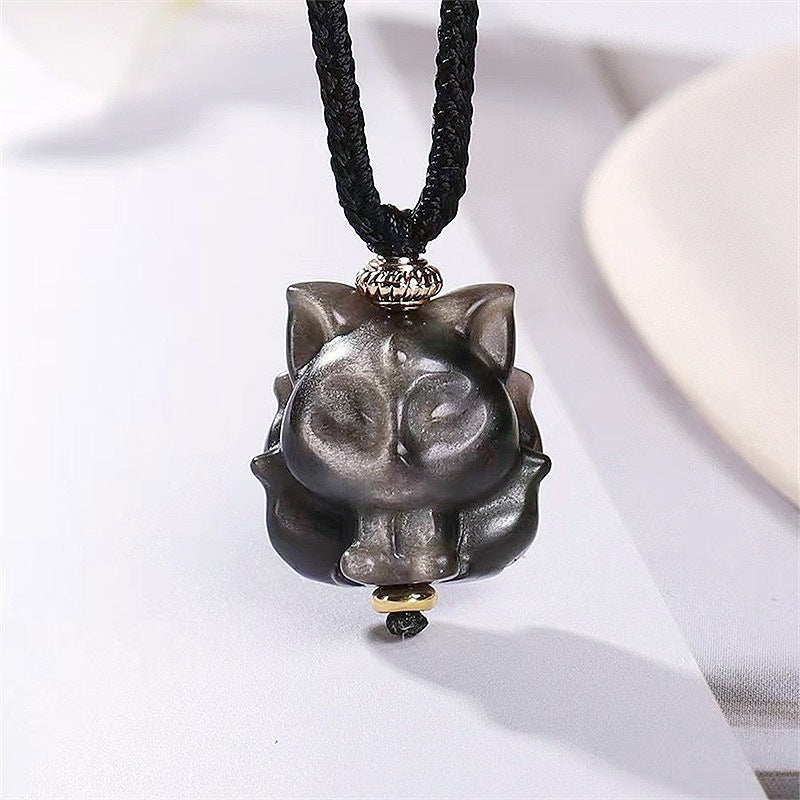 Close up view of a silver sheen obsidian fox pendant on a black cord
