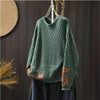 Green long sleeve crew neck women's sweater with floral patchwork details hanging on a wooden hanger