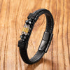 Black braided leather bracelet with a central gold and clear bead on a wood background