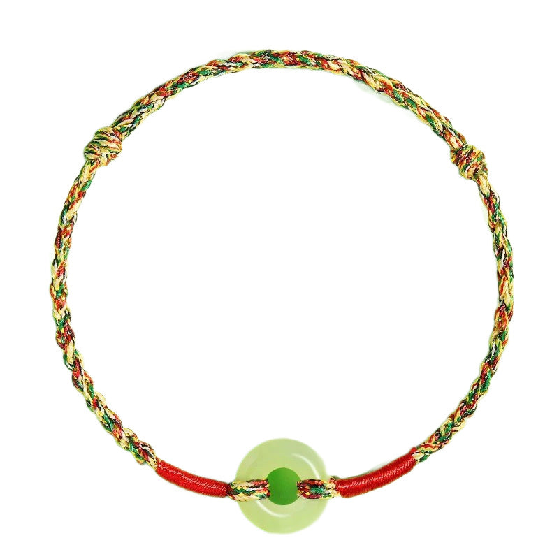 Close up of a multicolored woven rope bracelet with a light green jade donut charm