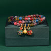 Triple wrap bracelet with colorful candy agate beads and gold-tone charms on a green box