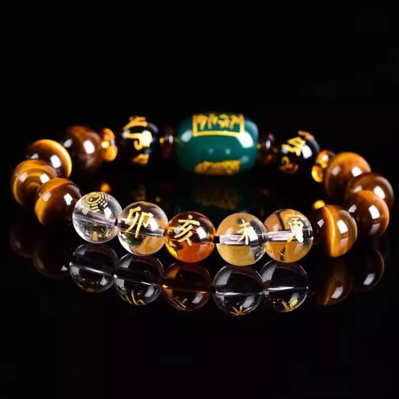 Close up of a Chinese Zodiac bracelet with tiger eye and green agate beads on a black background