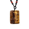Rectangular natural tiger eye pendant with a carved tiger design on a black cord