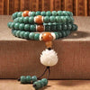 Green bodhi seed mala bracelet with white lotus pendant wrapped on a surface