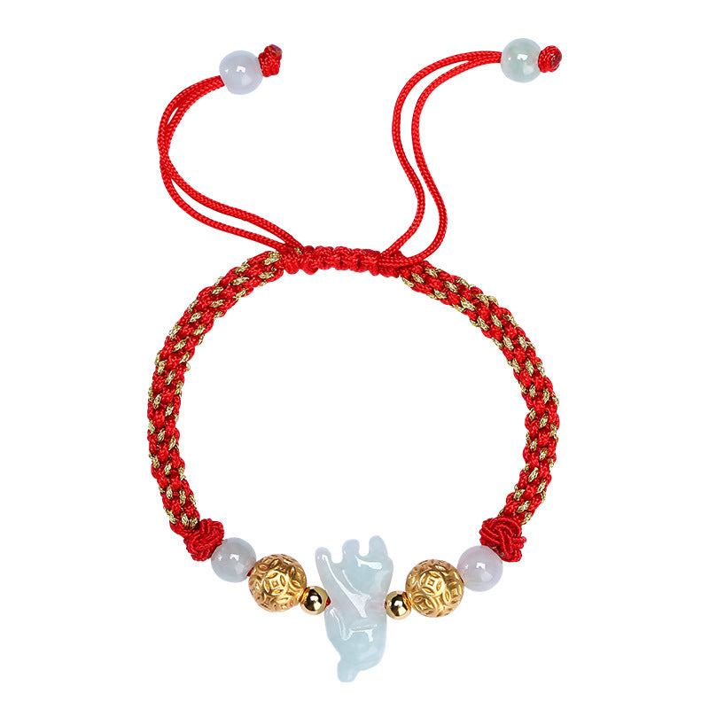 Close up of a red woven bracelet with a light green jade animal charm and silver beads