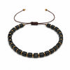 Black obsidian square bead bracelet with gold tone spacers on a dark background