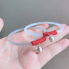 A hand holding two thin translucent agate bangles with red cord accents