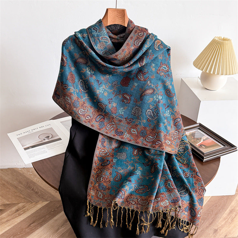 A long blue scarf with a brown paisley pattern and tassels draped over a mannequin.