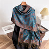 A long blue scarf with a brown paisley pattern and tassels draped over a mannequin.