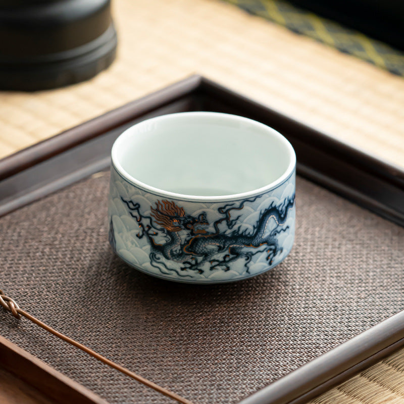 Blue and white ceramic teacup with dragon design on a wooden tray