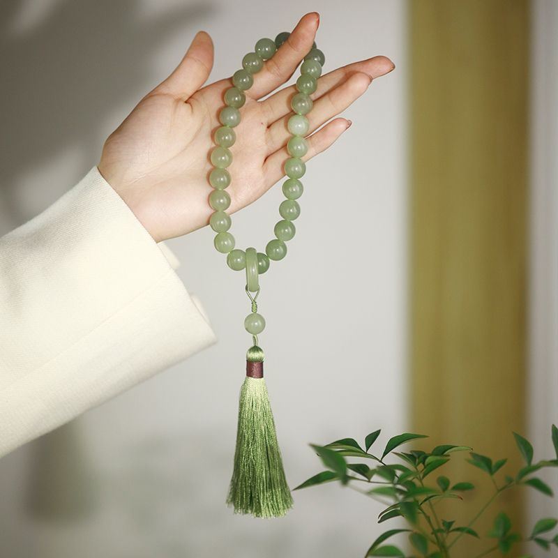 Hand holding a green beaded bracelet with a matching green tassel