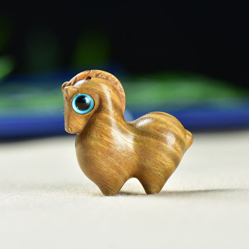Close up of a small light brown wooden horse carving with a blue eye.