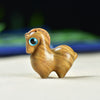 Close up of a small light brown wooden horse carving with a blue eye.