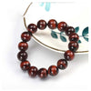 A close-up of a round beaded tiger eye bracelet resting on a white surface