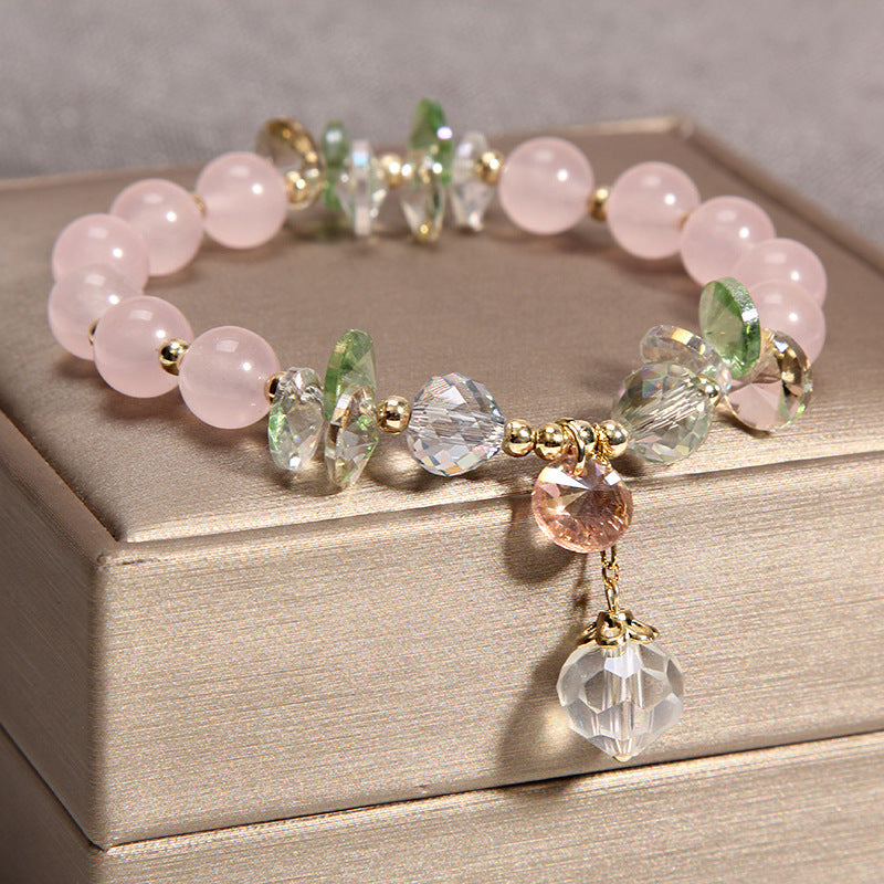 Close-up of a beaded crystal bracelet with gold-tone spacers and a hanging faceted charm