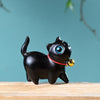 Close up of a black carved wood cat figurine with blue eyes and a red collar with a bell