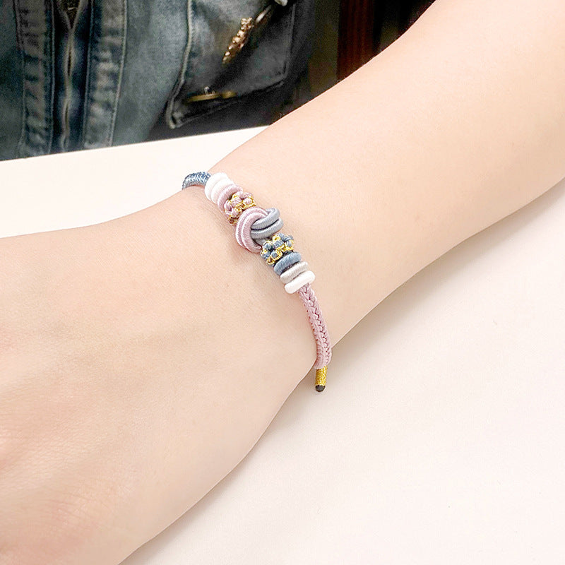 Close-up of a pink and blue woven bracelet with a central knot worn on a wrist