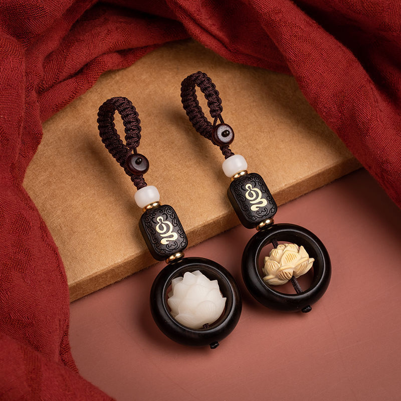 Close up of a dark wood keychain with a white carved lotus flower inside a ring