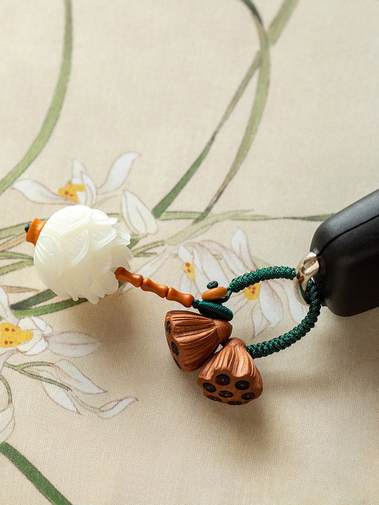 White bodhi seed lotus flower keychain with peach wood pods on green cord