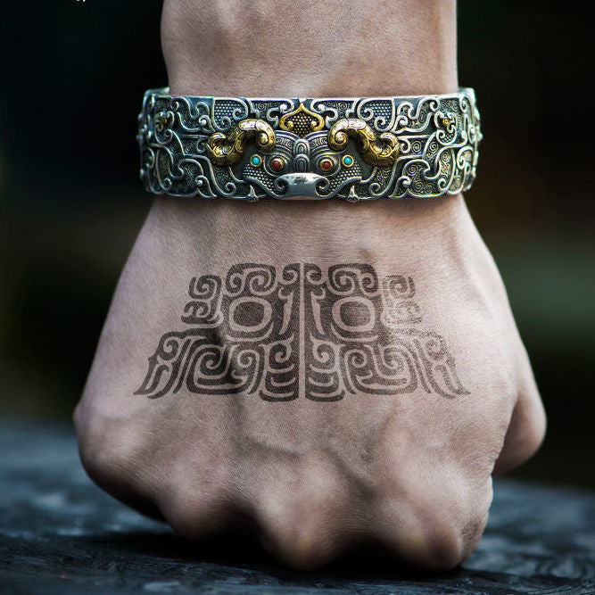 Wide copper cuff bracelet with engraved Pixiu design worn on wrist