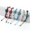 A collection of braided rope bracelets with turtle charms in various colors displayed on a white cylinder.