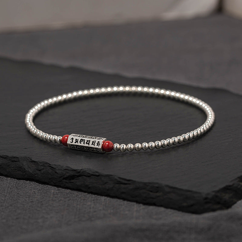 Silver tone beaded chain with red cinnabar beads and a mantra cylinder