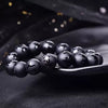 Close up of matte black agate beads with carved mantras on a dark surface