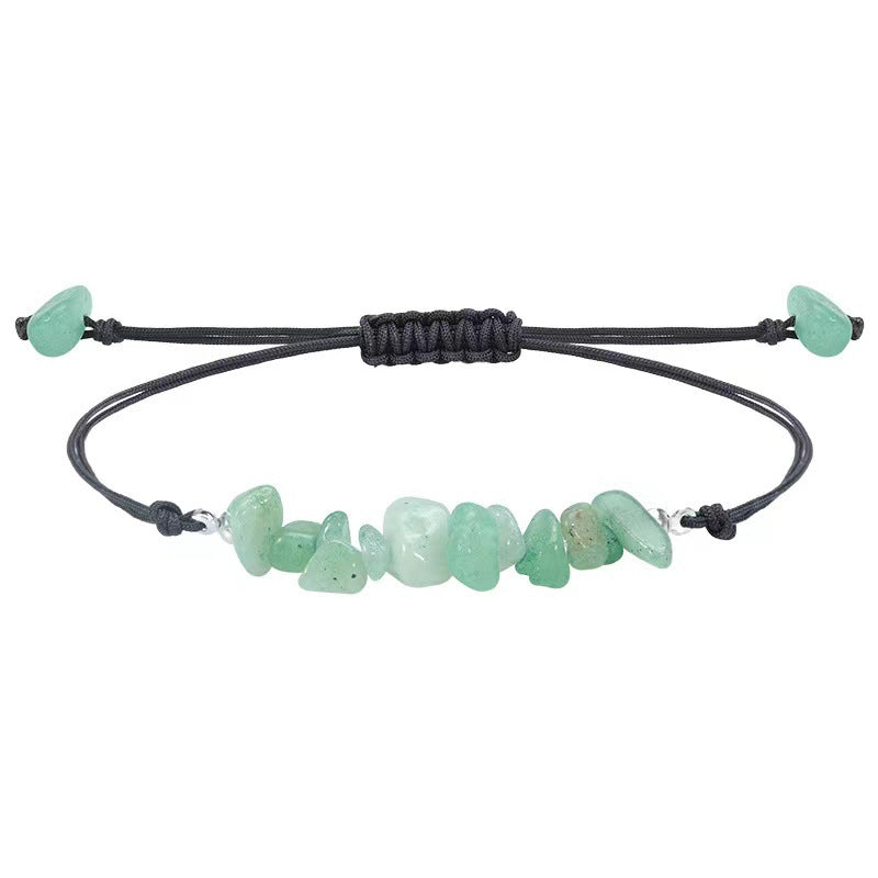 A close up of a green aventurine chip bracelet on a black cord with an adjustable sliding knot.