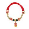 Red nylon pet collar with gold-tone metal ends and hanging charms including a fish and a character tag.
