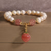 Close up of pearl bracelet with pink peach charm