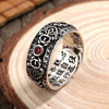 Close up of an adjustable copper ring with carved patterns and a red stone