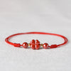 Red string bracelet with a central cinnabar four-leaf clover charm and round beads