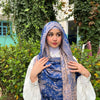 Woman wearing a blue patterned Tibetan shawl with tassels outdoors