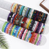 Rows of colorful natural stone beaded bracelets displayed on white cylinders