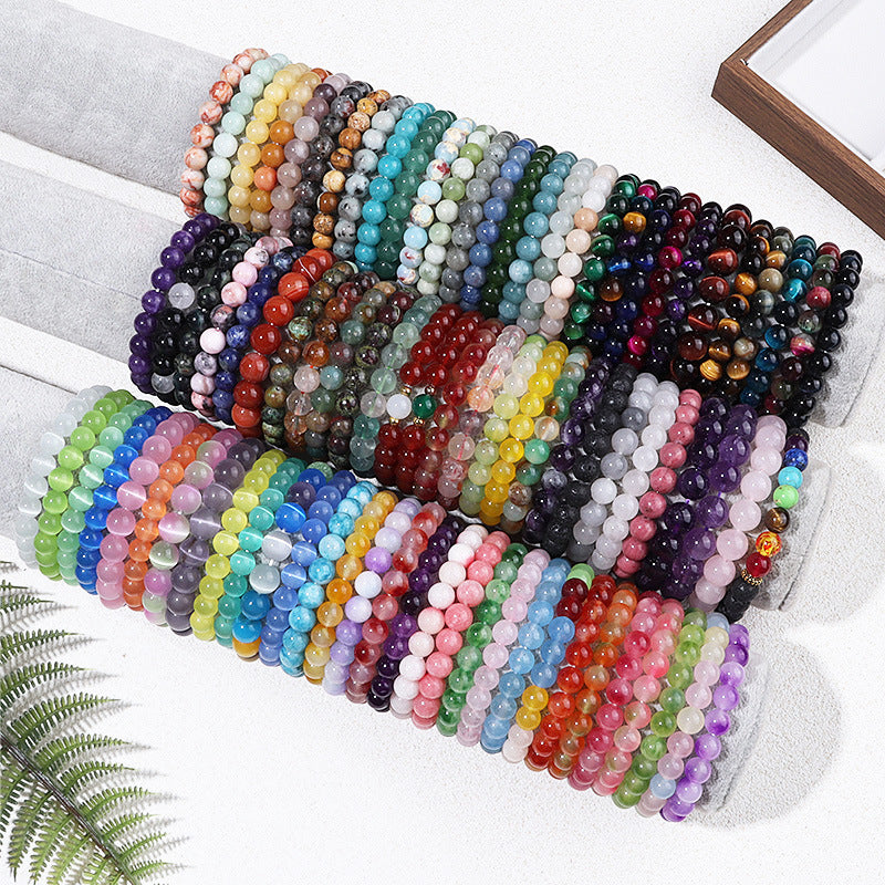 Rows of colorful natural stone beaded bracelets displayed on white cylinders