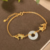 Gold-tone bracelet with white jade ring and two koi fish charms resting on a book