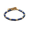 Blue lapis lazuli cylindrical bead bracelet with gold-tone spacers on a white background
