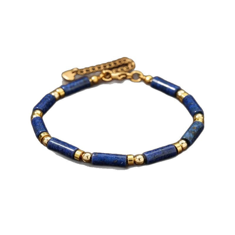 Blue lapis lazuli cylindrical bead bracelet with gold-tone spacers on a white background
