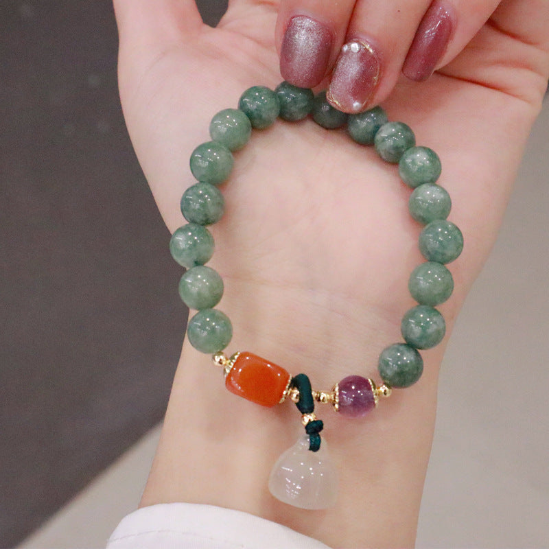 Green jade bead bracelet with orange and purple accents and a white lotus seed pod charm