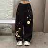 Black wide leg pants with gold moon and star print worn by a model