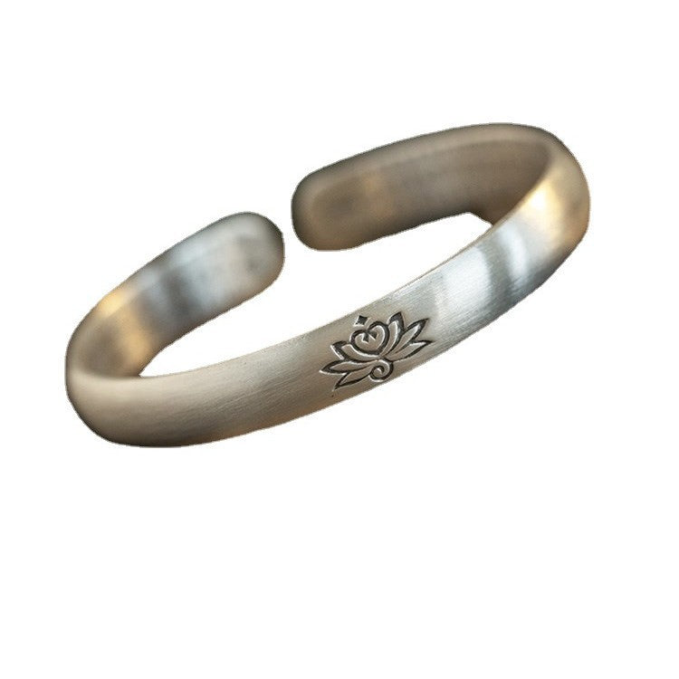 Close-up of a silver-plated white copper open bracelet with a lotus engraving worn on a wrist