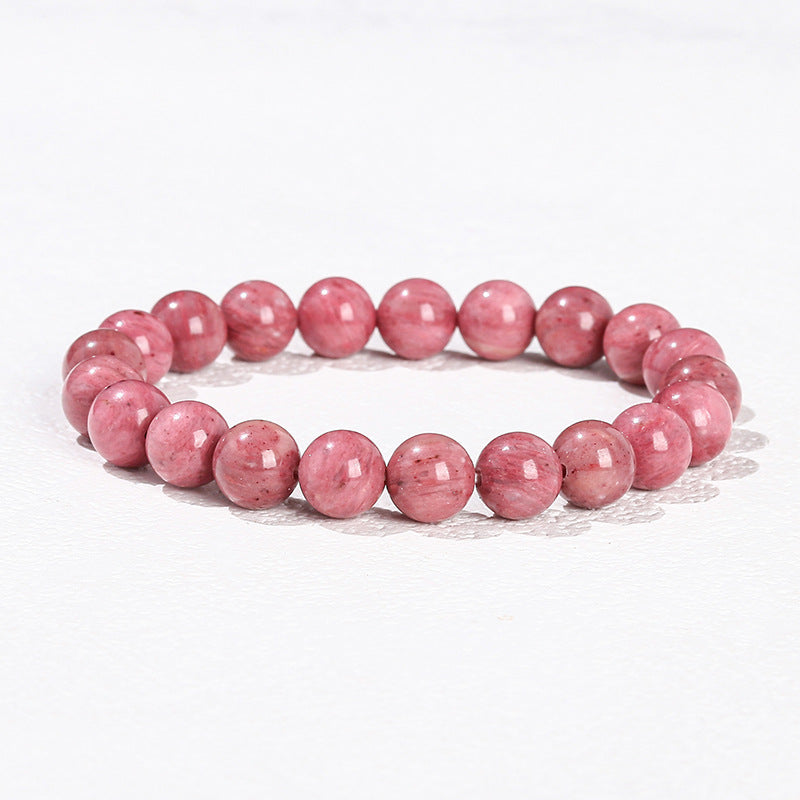 Close up view of a pink natural stone bead bracelet on a white background