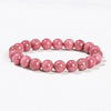 Close up view of a pink natural stone bead bracelet on a white background