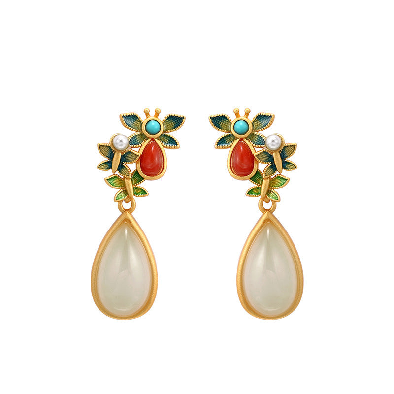 Gold-tone butterfly drop earrings with white faux jade and pearl accents resting on a book